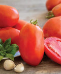 Gladiator Hybrid Red Tomato Seeds For Home Garden Non GMO Indeterminate Slicing And Paste Tomatoes on a wooden surface with herbs and garlic