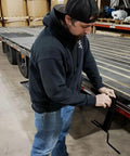 Man using Strap Winder For Flatbed Trailer Black Powder Coated Steel Cargo Tie Down Ratchet Strap Winder Winch Roller.