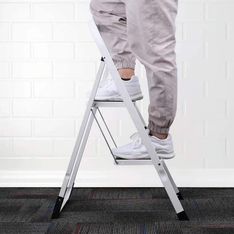 Person standing on GS Certified 2 Step Ladder Stool With Handle Grip Built Tough Anti Slip Rubber Feet Wide Pedal Lightweight Metal