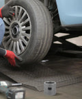 Mechanic with a tire and tool, showcasing weld-on mount for Swivel Mount Trailer Jack For Camper Welding, Carbon Steel Construction.
