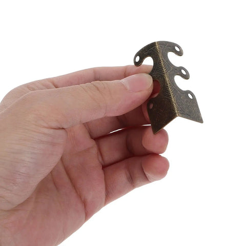 Hand holding Heavy Duty Antique Metal Corner Guard from 20 Pack for Cabinets and Albums Easy Install Decorative Alloy Corner Protectors
