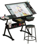 Premium Height Adjustable Tilting Drawing Desk With Tempered Glass Surface Featuring Killer Ergonomic Comfort And Smooth Glide Mechanics For Your Home Office Art Studio Boss Build, showing glass top and art supplies.