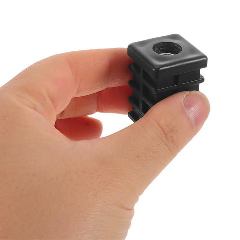 Close-up of a hand holding a black square cover from Plastic Tube End Caps And Adjustable Furniture Feet Pads Kit 12 Pieces With M8 Thread Integrated Nut.
