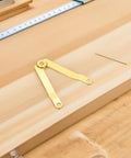 Golden Iron Lid Support Hinges for Jewelry Boxes and Treasure Chests, single hinge, wood background, close-up view