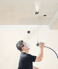 User demonstrating Pro Move Airless Paint Spray Gun And Hose Kit Featuring 3600 PSI Pressure Rating while painting ceiling.