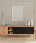 Modern living room with wooden cabinet, books, and vases on top, neutral decor style, wall art above, and chair on the side.