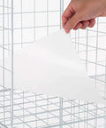 Hand placing shelf sheet in Premium Wire Cube Storage Organizer for home and garage, four cube shelving unit, DIY organizer.