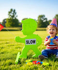 Kid Alert Street Safety Sign 31 Inch Green Caution Sign For Neighborhoods And Schools placed on grass with child nearby.