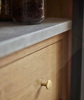 Champagne Bronze Kitchen Cabinet Knobs 6 Pack Round Modern Hardware For Cabinets And Dressers One And One Eighth Inch Diameter Fingerprint Resistant Brushed Finish Easy Install Chic Minimalist Look For Any Room installed on wood drawer under gray countertop.
