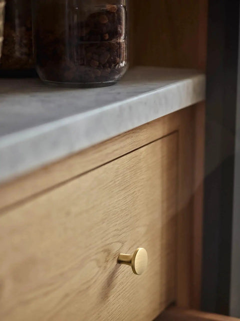 Champagne Bronze Kitchen Cabinet Knobs 6 Pack Round Modern Hardware For Cabinets And Dressers One And One Eighth Inch Diameter Fingerprint Resistant Brushed Finish Easy Install Chic Minimalist Look For Any Room installed on wood drawer under gray countertop.