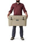 Heavy Duty 65 Quart Rotomolded Hard Shell Cooler Locks In Frost All Day Long To Keep Cold Brews And Fresh Catch Chilled For Tailgates Or Summer Getaways In Canopy Green held by a person.