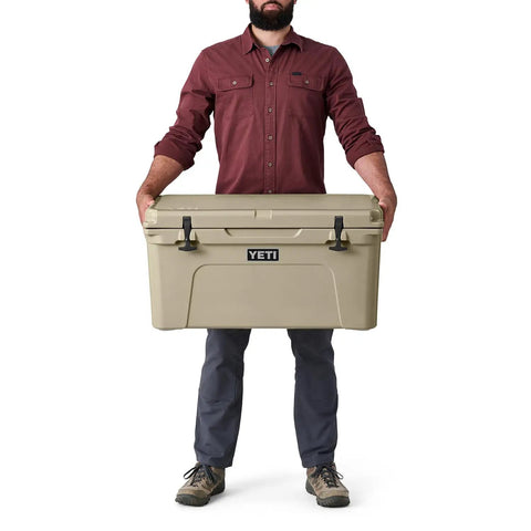 Heavy Duty 65 Quart Rotomolded Hard Shell Cooler Locks In Frost All Day Long To Keep Cold Brews And Fresh Catch Chilled For Tailgates Or Summer Getaways In Canopy Green held by a person.