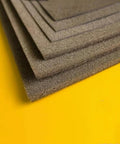 Side view of stacked dark gray metal conductive sponge sheets with adhesive