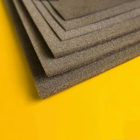 Side view of stacked dark gray metal conductive sponge sheets with adhesive
