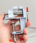 Tiny Bench Vise Clamp For Workbench And Diy Projects in hand, showing silver clamp mechanism and red handles for precise work
