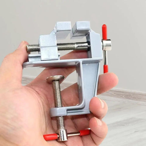 Tiny Bench Vise Clamp For Workbench And Diy Projects in hand, showing silver clamp mechanism and red handles for precise work