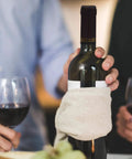 Person holding wine bottle with Pro Grade PVC Heat Shrink Capsules For Wine Bottles 100 Pack Black Sealer Shrink Caps, glasses nearby.