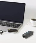 Compact USB Ham Radio Audio Interface With PTT Control For Yaesu And ICOM next to a laptop and coffee cup on a white desk.
