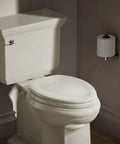 Molded Wood Elongated Toilet Seat In Almond With Color Matched Plastic Hinges Stonewood Style Built To Last For One And Two Piece Toilets Easy Install And Secure Fit Classic Look in a bathroom setting, closed position