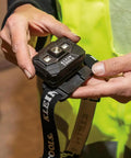 Person holding a headlamp bracket with comfy fabric strap for removable headlamps, marker and carpenter pencil holder, and mounting accessory.
