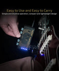 Hand holding USB Rechargeable Portable Pocket Guitar And Bass Headphone Amp with Plug In Multi Effects connected to guitar.