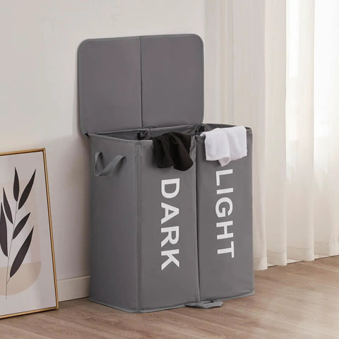 Big Ol Double Laundry Hamper With Lid And Removable Bags in gray, two-section basket labeled dark and light in a room setting