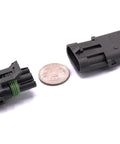 Two 3-pin waterproof electrical connectors with locking tabs, black housings, green gasket and blue/white wires.