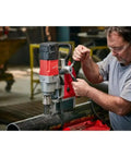Heavy Duty 1-5/8 Inch Magnetic Drill Base For Milwaukee Power Tools being used on a pipe with precision cutting in a workshop.