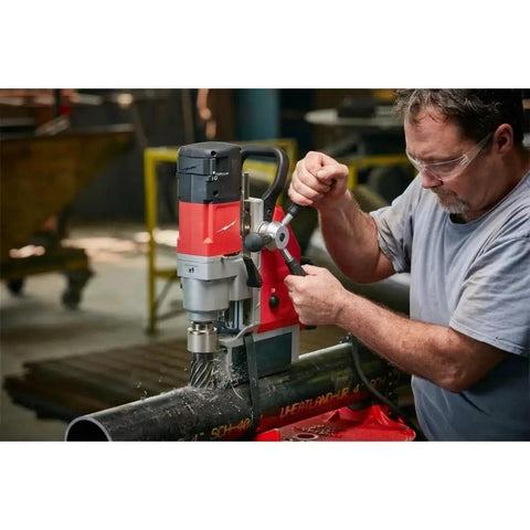 Heavy Duty 1-5/8 Inch Magnetic Drill Base For Milwaukee Power Tools being used on a pipe with precision cutting in a workshop.