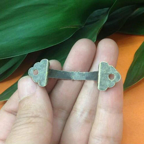 Close-up of antique brass zinc alloy mini jewelry box drawer cabinet pull handle from 10 pack, held in hand, vintage look, with 38mm hole spacing.