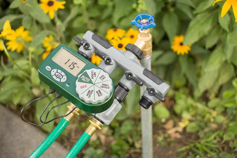 Automatic Yard Watering System With Four Station Sprinkler Setup attached to garden faucet with digital display and hose connections.