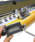 Rugged Hand Held Manual Tally Counter For Cranking Out Totals On The Fly With Crisp Five Digit Dial in use on a printing machine.