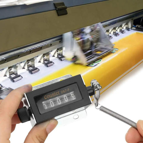 Rugged Hand Held Manual Tally Counter For Cranking Out Totals On The Fly With Crisp Five Digit Dial in use on a printing machine.