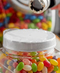 Clear Tamper Evident Heat Shrink Bands That Fit Snug And Lock Down Solid For 89Mm Caps With Max 3.5 Inch Diameter Non Perforated Safety Sealing For Jars Bottles And Containers on a jar lid with colorful jelly beans visible.