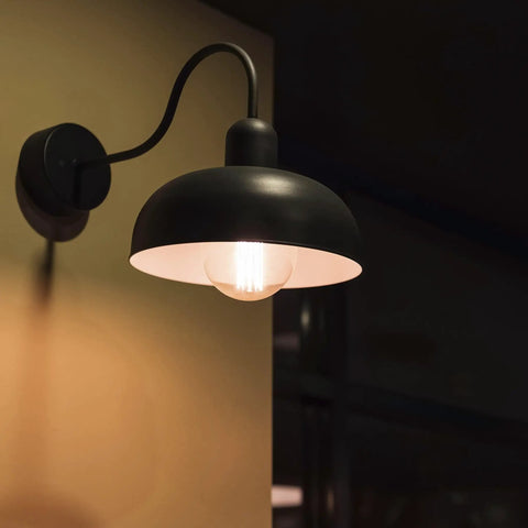 G25 LED Filament Vanity Bulb 40W Equivalent lit in black wall sconce, emitting warm glow, 500 Lumens, 2700K Warm White