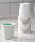 Stack of 6 Oz White Paper Cups 300 Count Small Disposable Cups For Espresso Tea Tastings Mouthwash And Samples on counter.
