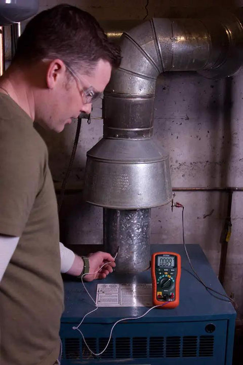 Technician using Datalogging Cat IV True RMS Multimeter With Bluetooth Connectivity for temperature measurement on industrial unit.