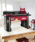 All In One Router Table And 10 Amp Fixed Base Router Kit setup on wooden workbench in a workshop environment.