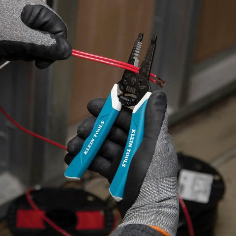 Hand using Pro Grade Wire Stripper And Cutter For 8 To 18 AWG Solid And 10 To 20 AWG Stranded Wire With Six Precision Ground Stripping Holes Narrow Head For Tight Corners Made In USA Durable Hand Tool For DIY And Pros on red wire