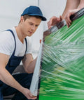 Heavy Duty Stretch Wrap Roll Pro Grade 18-Inch By 1500-Foot Clear Shrink Film for Furniture Moving shown in use by worker.