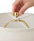 Hands installing the Rock Solid 2 Pack Short Lamp Harp 6 Inch Antique Gold Shade Bracket on a lamp shade.