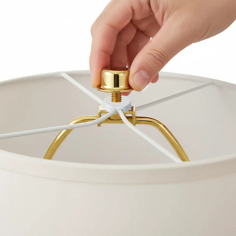 Hands installing the Rock Solid 2 Pack Short Lamp Harp 6 Inch Antique Gold Shade Bracket on a lamp shade.