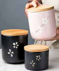 Matte Black Ceramic Coffee Canister With Premium Airtight Seal Keeps Your Daily Grind Fresh No Fuss Wide Mouth Design For Easy Scooping And Reliable Kitchen Pantry Storage in hand with pink jar.