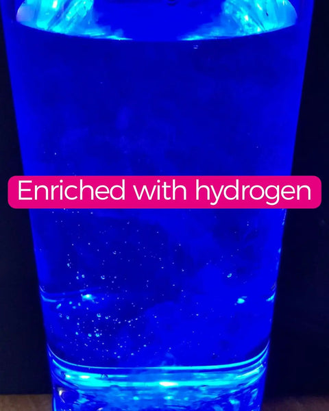 Blue hydrogen-enriched water inside a clear bottle, glowing under light, displaying the text 'Enriched with hydrogen'.