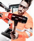 Person using Soft Face Mallet Workhorse with Dual Inserts, black rubber and red plastic, cast iron housing on a construction site
