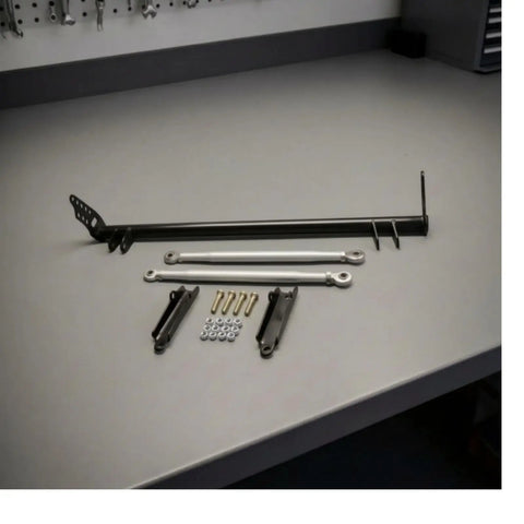 Heavy Duty Rear Traction Control Rod Assembly And Chassis Brace Kit Featuring Carbon Steel Build To Kill Wheel Hop While Beefing Up Sedan Rigidity For Strong Launches And Tight Cornering With 1992 Through 1995 Fitment, with various components on a worktable.