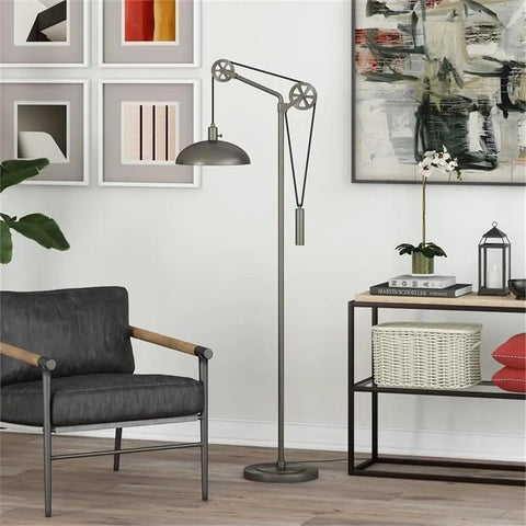 Spoke Wheel Pulley Floor Lamp With Metal Shade In Aged Steel Finish next to chair and artwork, industrial decor