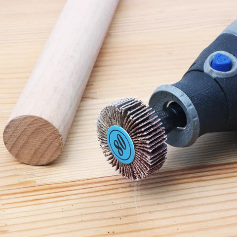 Close-up of a rotary tool with 20 Pack 80 Grit Flap Wheel Sander Set With Pro Grade One Eighth Inch Shank on a wooden surface