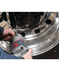 Pro Level One Inch Drive Air Impact Wrench in use, gripping heavy-duty tool for lug nut removal on polished wheel.