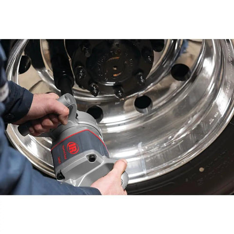 Pro Level One Inch Drive Air Impact Wrench in use, gripping heavy-duty tool for lug nut removal on polished wheel.